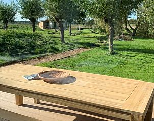 Wooden dining table on terrace of cottage in Kamperland, surrounded by nature in Zeeland.