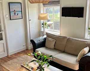 Comfortabele woonkamer in Vakantiehuisje in Kamperland met grote ramen en natuurlijk licht.