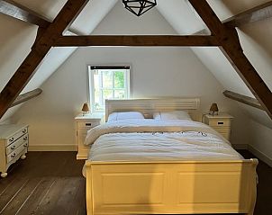 Slaapkamer in Vakantiehuisje in Kamperland met houten balken en een knus bed.