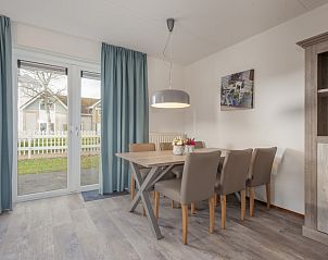 Gemtliches Esszimmer in der Villa R5B, einem Ferienhaus in Kamperland, Nord-Beveland, mit Blick auf den Garten durch groe Fenster.