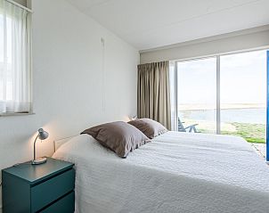 Slaapkamer in Ostrea 25 | Roompot Beach Resort, vakantiehuis in Kamperland, met groot raam en uitzicht op het water.