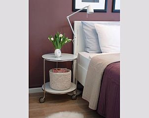 Nachttisch und Dekoration im Schlafzimmer des Ferienhauses VZ1178 in Kamperland, mit Tulpen und Uhr.