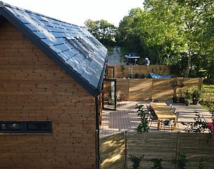 Seitenansicht des Ferienhauses in Kamperland, Nord-Beveland, mit groer Terrasse und grner Umgebung.