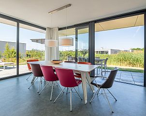 Eetkamer met kleurrijke stoelen in Zandbank 21 | De Groote Duynen, Noord-Beveland, met uitzicht op de natuur.