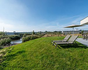 Zonnige tuin met ligstoelen bij Duinvallei 12, vakantieaccommodatie in Kamperland, Zeeland.