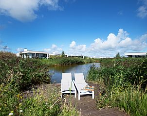 Zonnig terras met ligstoelen bij Zandbank 11 | De Groote Duynen, Kamperland, met uitzicht op het water en groene omgeving.