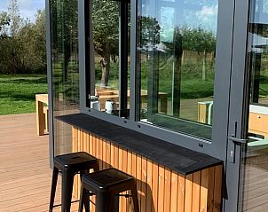 Outdoor terrace of vacation home in Kamperland with bar and stools, ideal for relaxation in North Beveland, Zeeland.