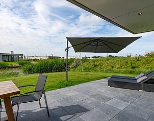 Terras van Duinvallei 22, vakantiehuis in Kamperland, Noord-Beveland, met parasol en uitzicht op de groene omgeving van Zeeland.