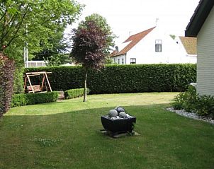 Ruime tuin van Mi Casa, Burgh-Haamstede, met schommel en groen uitzicht, ideaal voor ontspanning in Zeeland.