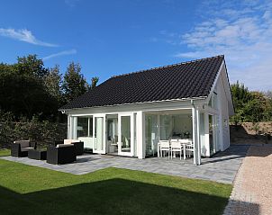 Vacation home Zonnedorp 4, Villa Jula in Renesse offers a sunny terrace with modern furniture in a green setting.