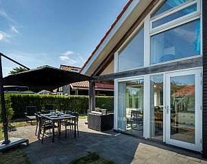Buitenterras van Vakantiehuis Zonnedorp 1, Solskin in Renesse met eettafel en parasol voor gezellige maaltijden.