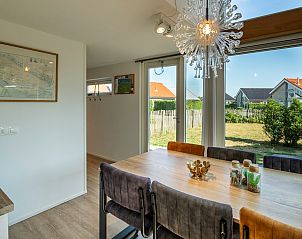 Eetkamer met grote ramen en uitzicht op de tuin in Vakantiehuis Zonnedorp 1, Solskin in Renesse.