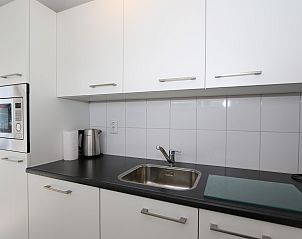 Stylish kitchen in Holiday Home Zonnedorp 18, Duinhuis 18 in Renesse, Zeeland with white cabinets and appliances.