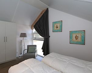 Modern bedroom in Holiday home Zonnedorp 18, Duinhuis 18 in Renesse, Zeeland with comfortable chair.
