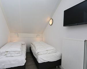 Double bed in attic room of Holiday home Zonnedorp 28 in Renesse, Zeeland.