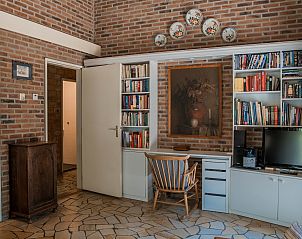Bibliotheekhoek in Vakantiewoning Kamperfoelieweg 13, Nieuw-Haamstede met boekenkast en schilderijen aan de muur.
