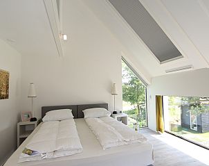 Lichte slaapkamer met groot raam in Vakantiehuis Duinhuis 11, Noordwelle, Schouwen-Duiveland, met uitzicht op de tuin.