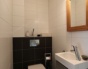 Compacte badkamer met wastafel en spiegel in Vakantiehuis Duinhuis 11, Noordwelle, Schouwen-Duiveland, met strakke afwerking.