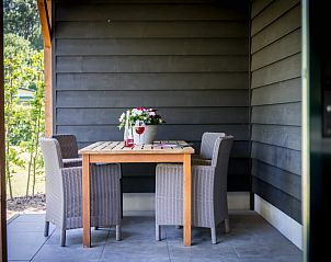 Overdekte veranda met eettafel in Vakantiehuisje in Noordwelle, buitenruimte in Schouwen-Duiveland, Zeeland.