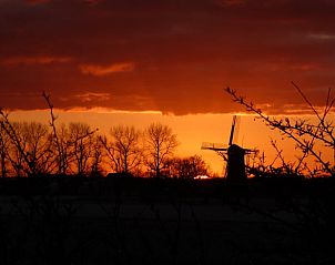 Prachtige zonsondergang bij Vakantiehuis in Zonnemaire met molen in de verte, Zeeland.