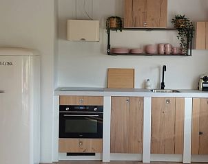 Grote keuken in Vakantiehuis in Noordgouwe met moderne apparatuur en houten afwerking.