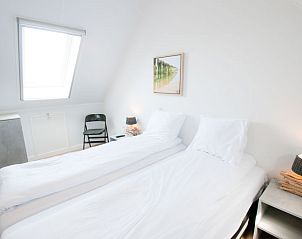 Lichte slaapkamer met kunstwerk in Vakantiehuis Oesterdam Resort in Tholen, Zeeland.