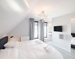 Lichte slaapkamer in Vakantiehuis Oesterdam Resort, Tholen, Zeeland met moderne inrichting en televisie.