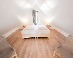 Lichte slaapkamer op zolder in Vakantiehuis Oesterdam Resort, Tholen, Zeeland met houten vloer.