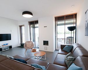 Gezellige zithoek met moderne inrichting in Vakantiehuis Oesterdam Resort, Tholen, met uitzicht op het water.