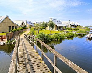 Schilderachtig pad langs het water bij Vakantiehuis Oesterdam Resort, Tholen, met vakantiehuizen op de achtergrond.