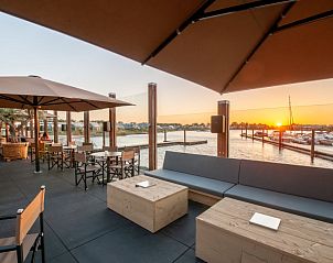 Buitenterras met uitzicht op de jachthaven bij zonsondergang bij Vakantiehuis Oesterdam Resort, Tholen.