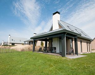Vakantiehuis met groot terras bij Oesterdam Resort in Tholen, Zeeland, omgeven door groen gras.