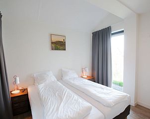 Slaapkamer met tweepersoonsbed in Vakantiehuis Oesterdam Resort, Tholen, met uitzicht op de tuin.