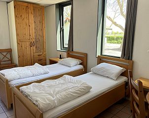 Slaapkamer in VZ033 Appartement Koudekerke met comfortabele bedden en uitzicht op tuin.