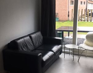 Woonkamer met leren bank in Vakantiehuisje in Koudekerke, Walcheren, met uitzicht op de tuin.