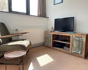 Stijlvolle hoek met fauteuil en tv in VZ035/VZ036 Appartement Koudekerke, Walcheren, ideaal voor ontspanning.
