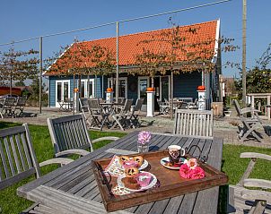 Auenterrasse des Ferienhauses 'T Bloemenhof Koudekerke mit Holztischen und Sthlen, Walcheren, Zeeland.