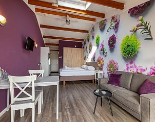 Offener Wohnraum im Ferienhaus 'T Bloemenhof Koudekerke mit bunten Blumenakzenten, Walcheren, Zeeland.