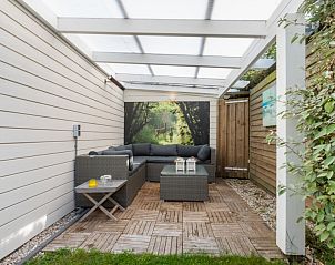 Overdekte zithoek in de tuin van Loopafstand strand en bos - Oostkapelle, vakantiehuis in Oostkapelle, Walcheren, met loungebank.