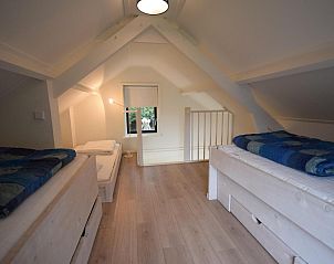 Mansardenzimmer mit Betten im Ferienhaus VZ1158 in Oostkapelle, Walcheren, mit Holzbalken im Dach.