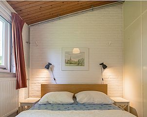 Comfortabele slaapkamer in VZ1182 Vakantiebungalow in Oostkapelle, Walcheren, met raam en kunst.