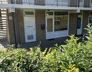 Entree van VZ069 Vakantieappartement Oostkapelle, Walcheren, met groene struiken en zonnige uitstraling.
