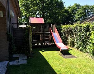 Speeltuin met glijbaan in de tuin van vakantiehuis ZE320 in Oostkapelle, Walcheren, voor kinderen.
