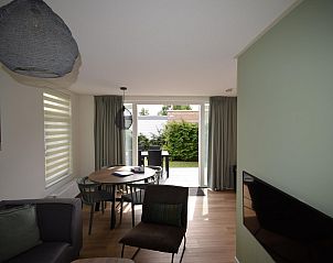 Gezellige woonkamer van VZ1078 Vakantiehuis in Oostkapelle met eethoek en tuinzicht.