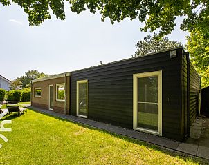 Green garden of vacation home ZE145 in Oostkapelle, Walcheren, with comfortable seating areas.