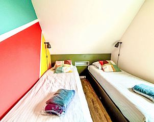 Kleurrijke slaapkamer in Appartement Beach House Westkapelle 107.6, Westkapelle, Zeeland met comfortabele bedden.