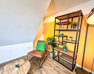 Stijlvolle leeshoek in Appartement Beach House Westkapelle 107.6, Westkapelle met comfortabele stoel en boekenplank.