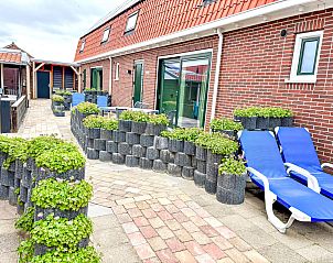 Veranda des Ferienhauses Beach House Westkapelle 103 D in Westkapelle, Walcheren, mit Sonnenliegen und modernem Mobiliar.