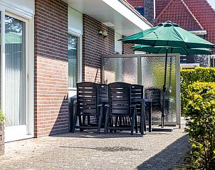 Auenterrasse des Ferienhauses ZE014, Domburg, Walcheren, mit Sitzgelegenheit und Sonnenschirm, ideal fr Mahlzeiten im Freien.