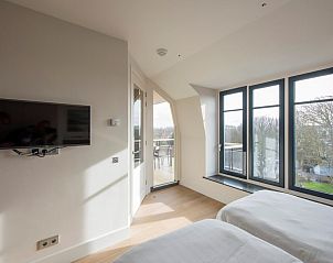 Slaapkamer in Champagne Wellness 6 in Domburg, Zeeland met grote ramen en uitzicht op de omgeving.